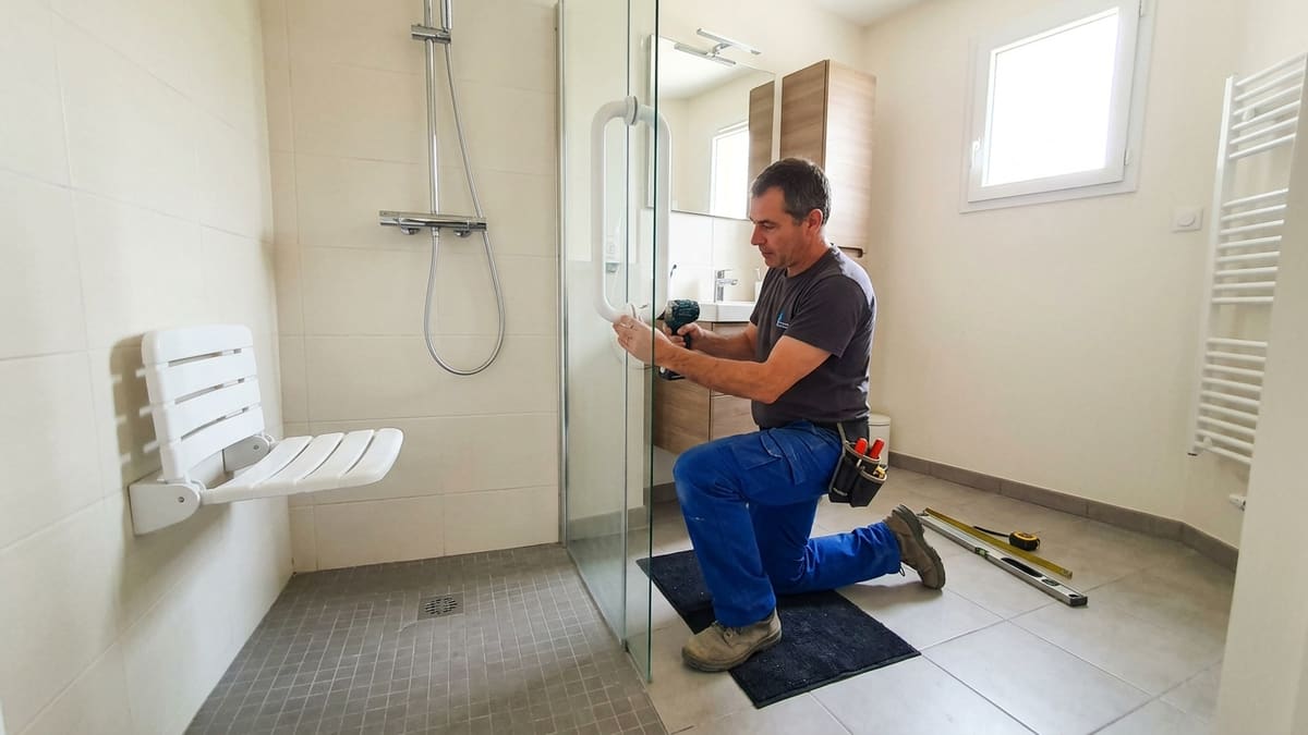 Artisan installant une douche sécurisée pour personne âgée avec siège